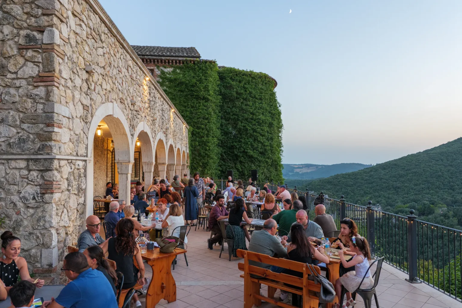 La terrazza Opera Social Club al tramonto, con tavoli e vista sulla valle